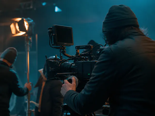 Anonymous camera operator and crew working on a blue-and-amber lit film set